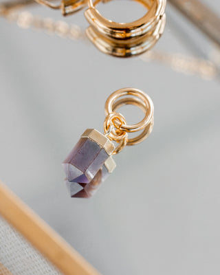 Coffee moonstone earring faceted pendant with gold hoop on a mirrored surface.