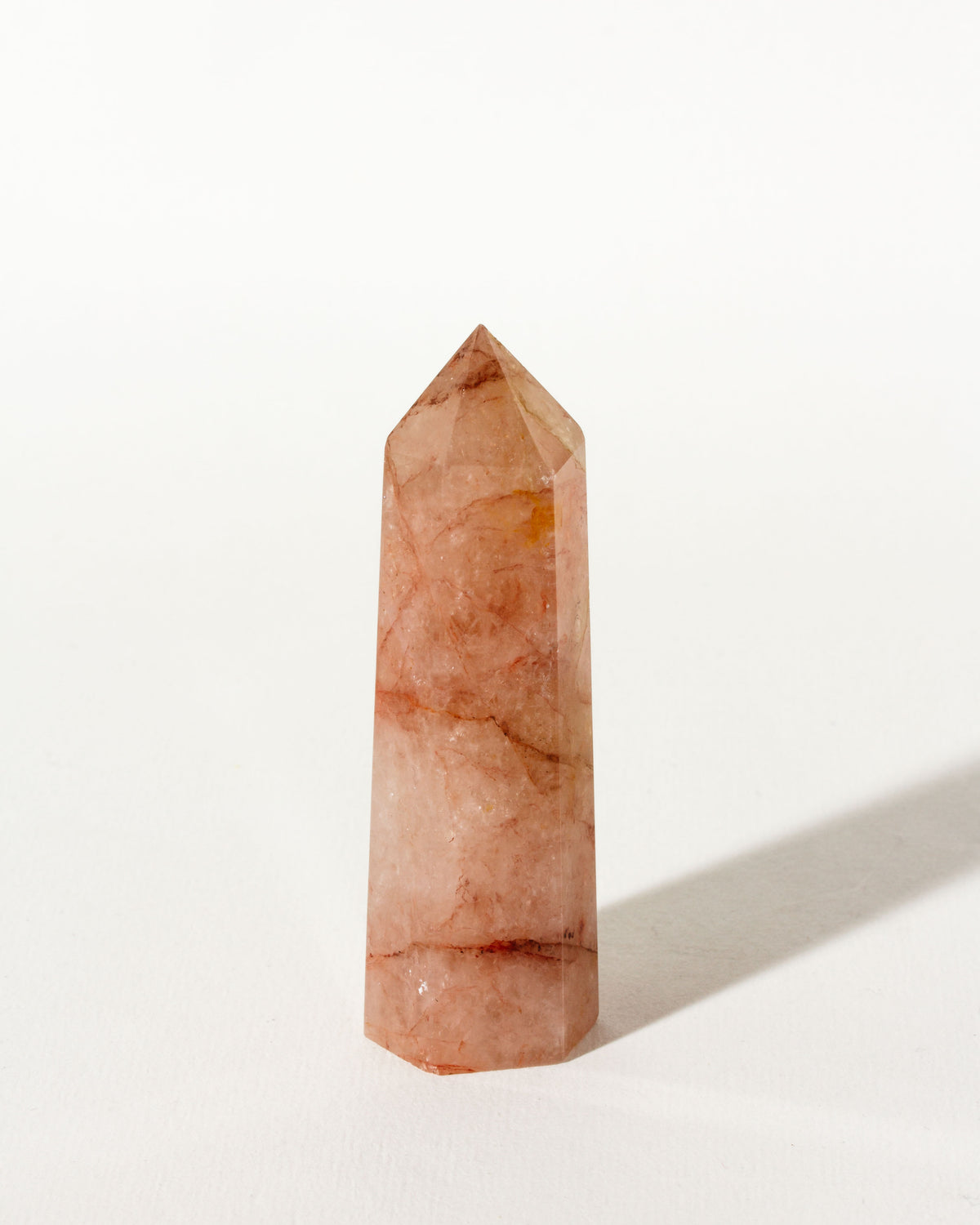 A polished Strawberry Quartz gemstone tower on a white background