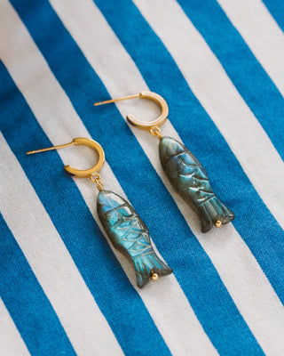 Fish-shaped labradorite earrings on a blue and white striped fabric background