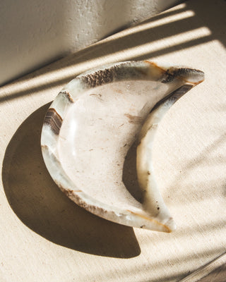 A moon-shaped catch-all dish, carved from genuine grayish calcite, displayed on a light background with shadows.