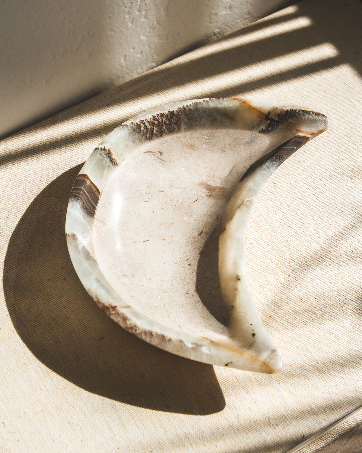 A moon-shaped catch-all dish, carved from grayish calcite