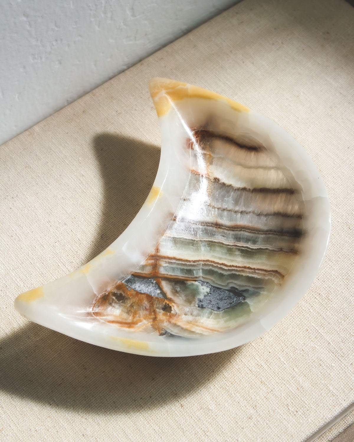 A moon-shaped catch-all dish, carved from multicolored calcite