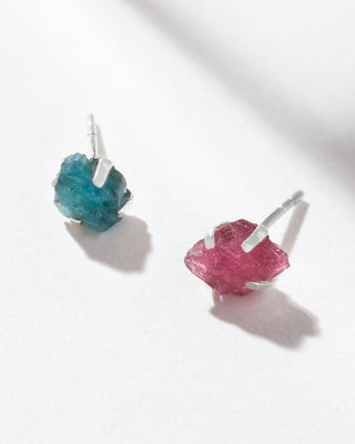 A pair of post earrings featuring raw-cut genuine tourmaline stones in pink and teal hues, set in sterling silver.