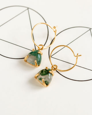 A pair of gold hoop earrings with green moss agate stones, displayed against a white background with a circular frame.