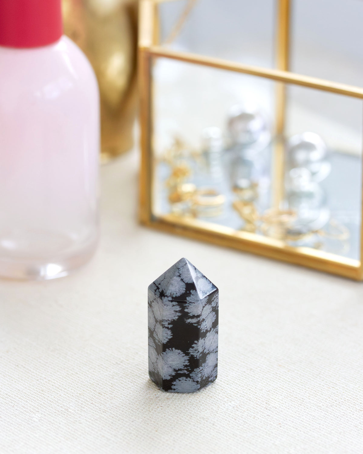 A mini snowflake obsidian gemstone tower with a black background and gray dusting