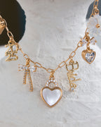 Gold necklace with various charms on a textured white surface