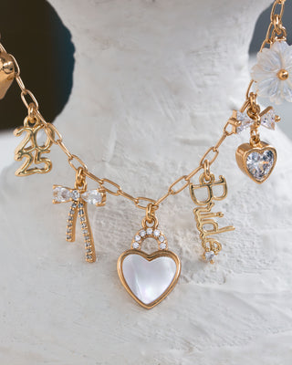 Gold necklace with various charms on a textured white surface