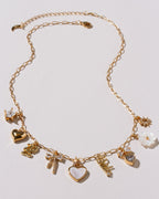 Gold necklace with various charms on a light white background