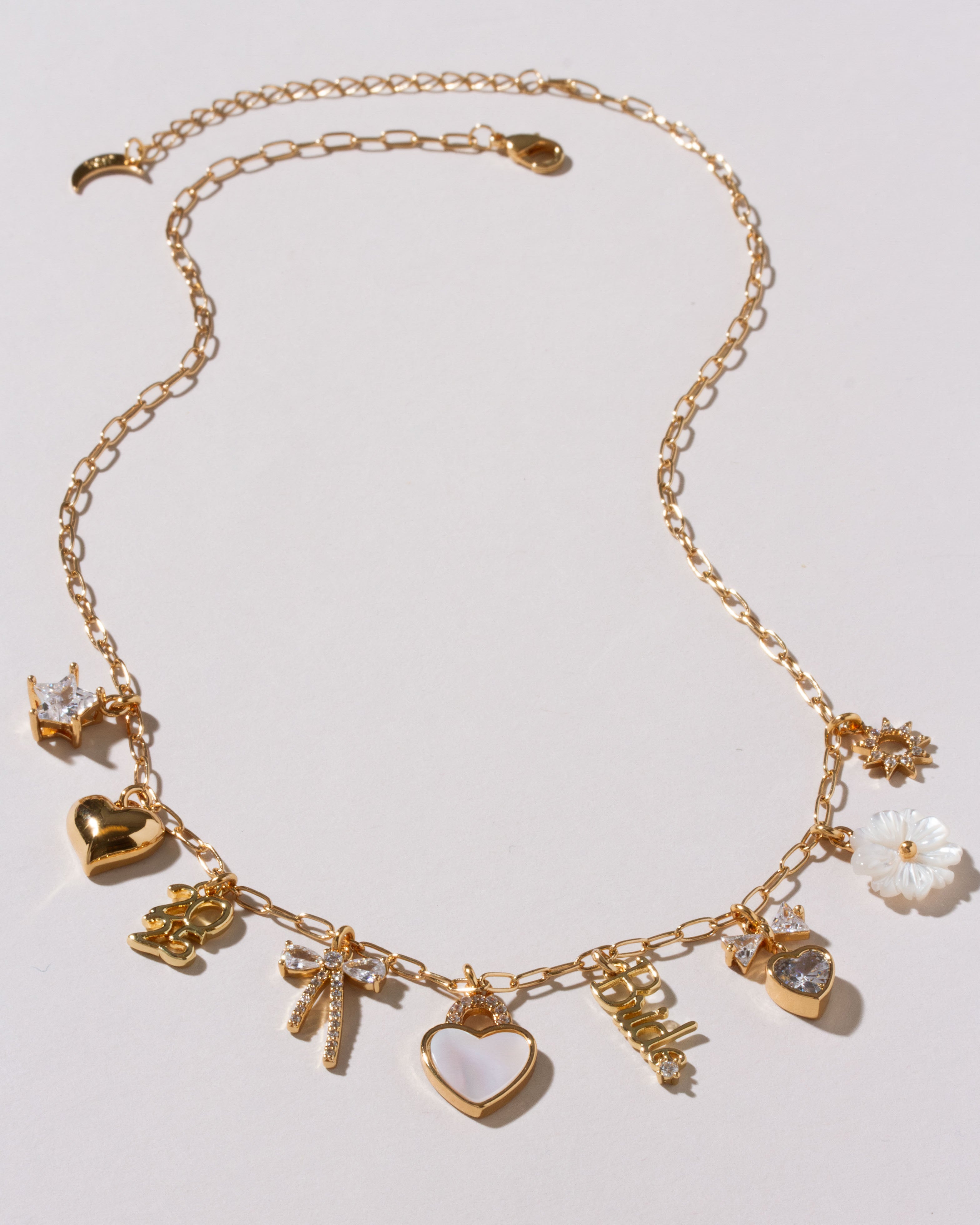 Gold necklace with various charms on a light white background