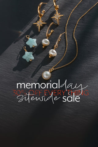 Jewelry set with necklaces and earrings displayed on a dark surface, with a promotional message for a memorial sale that reads "memorial day sitewide sale 30% off everything"