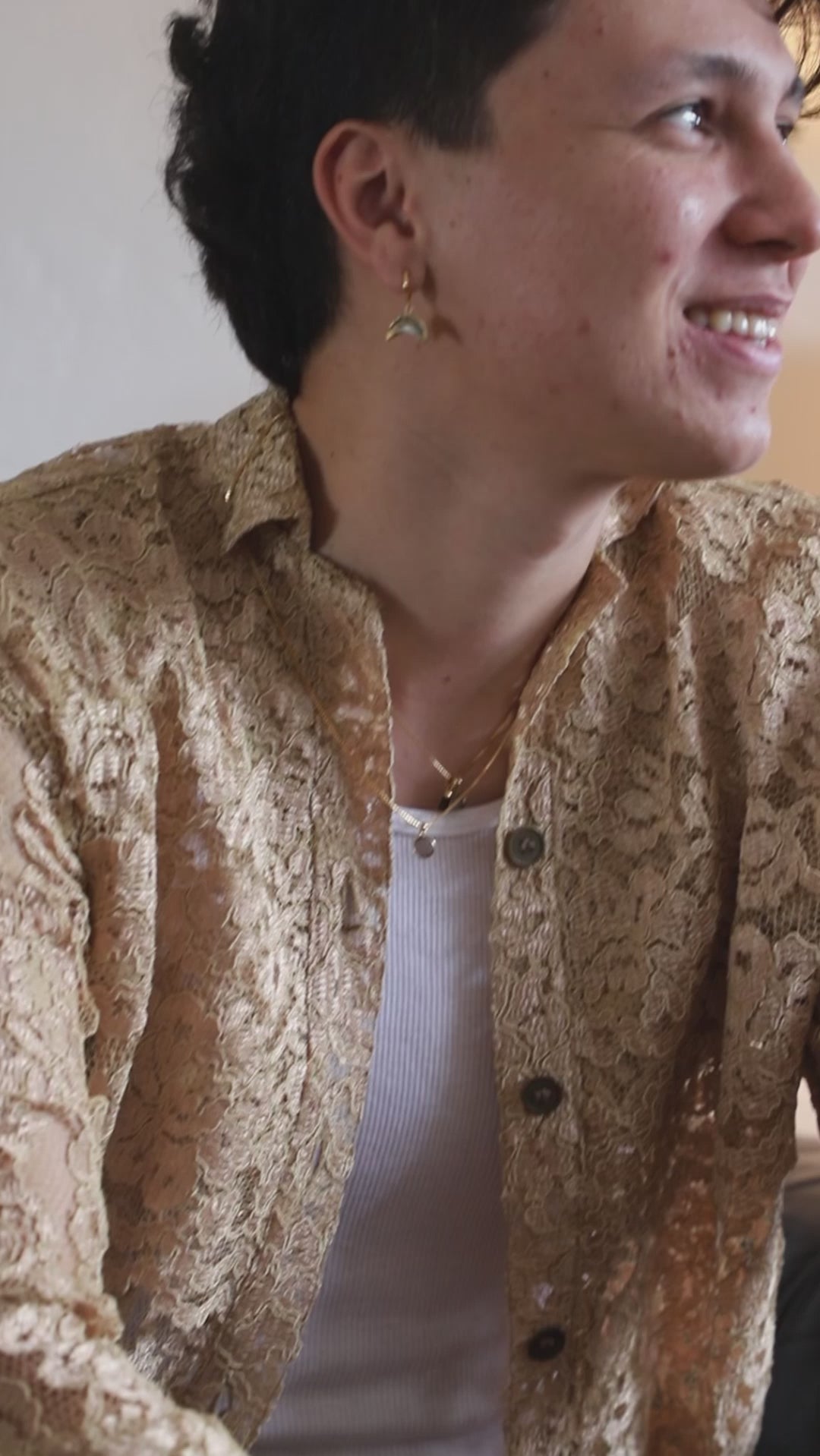 Person with many layered necklaces and crescent moon charm earring.