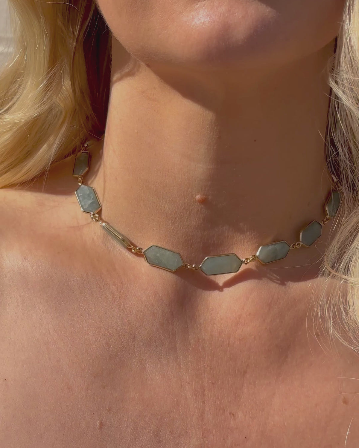 Closeup of woman wearing gold labradorite necklace and bracelets