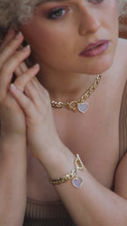woman posing with both gold toggle necklace and matching bracelet with heart shaped moonstone charms. 