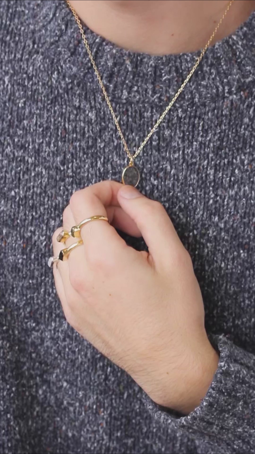 person wearing many gemstone rings and s simple gold chain gemstone necklace 