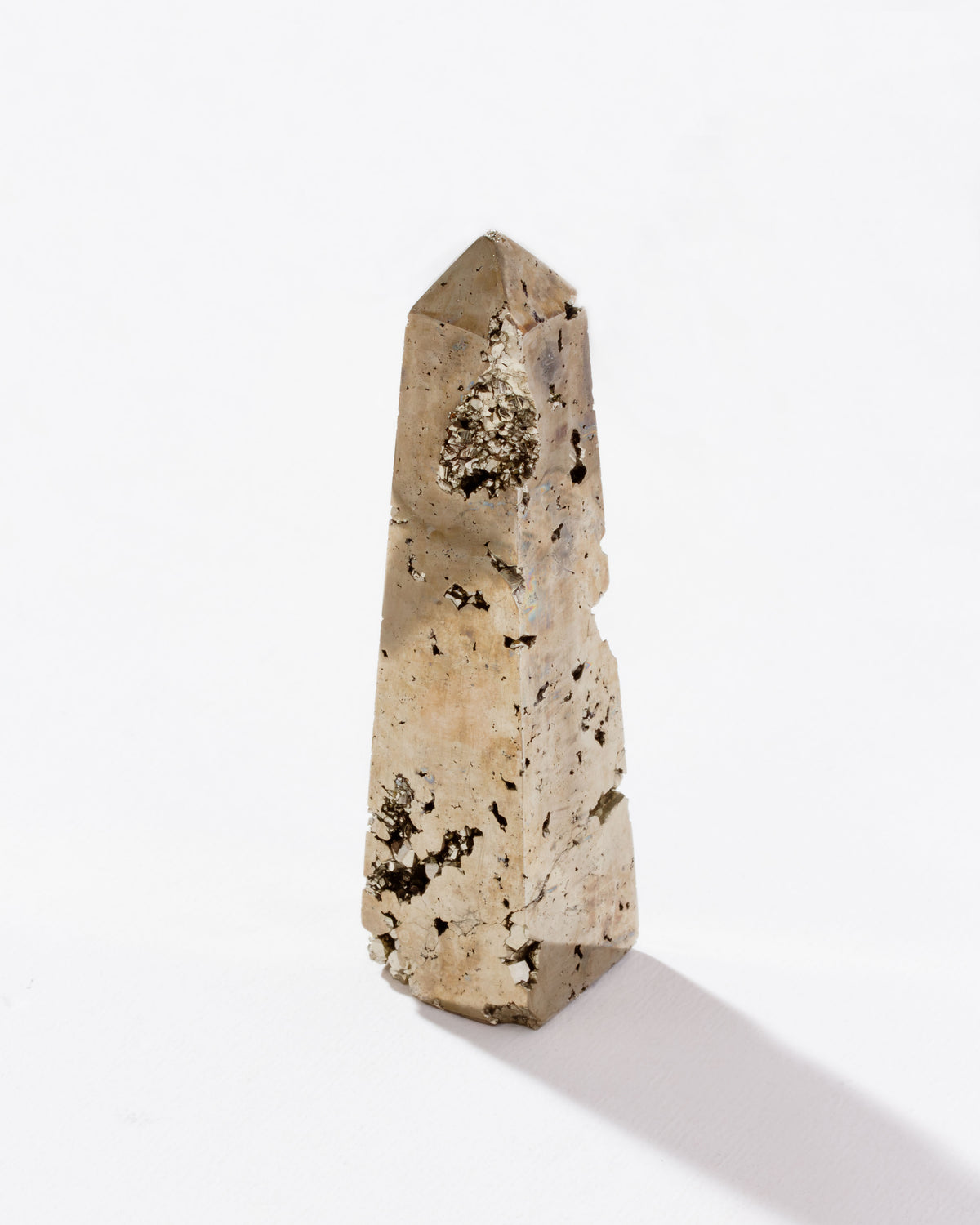 Gold colored, pyrite obelisk tower standing against the white surface.
