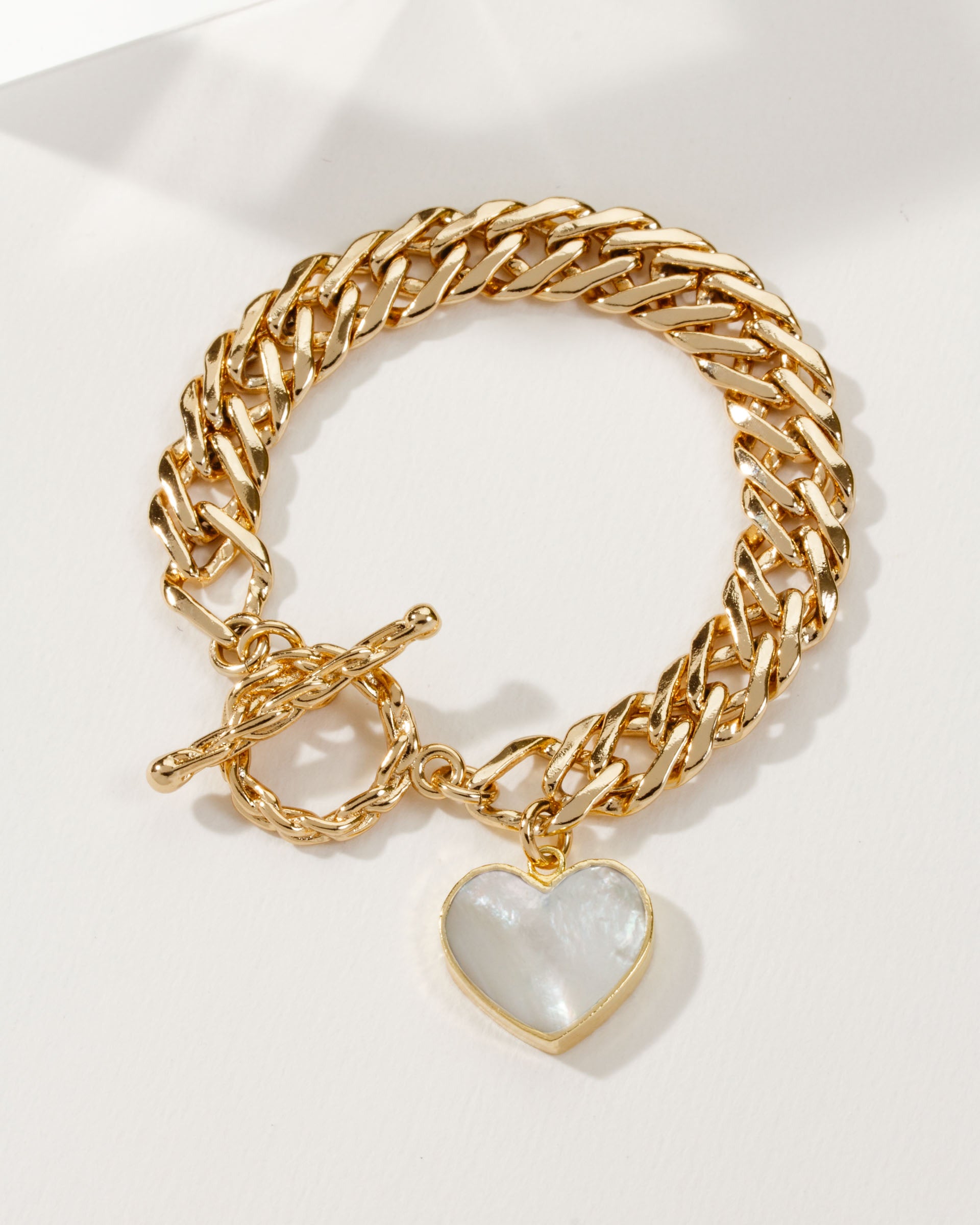 Gold chain toggle bracelet with a Mother of Pearl heart pendant.