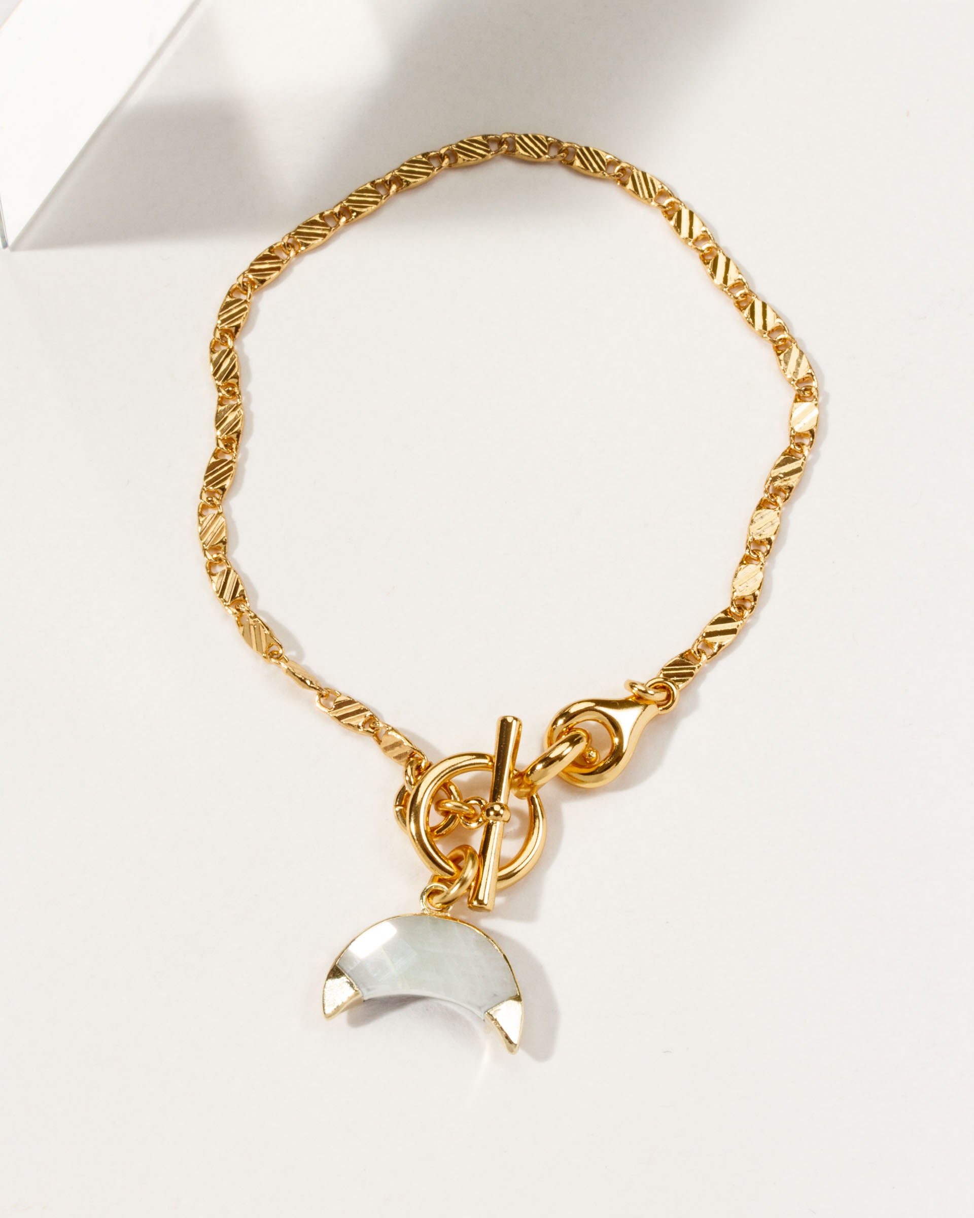 Gold chain bracelet with a moonstone crescent horn toggle.