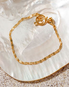 Gold-plated Adorned Toggle Bracelet on a pearlescent surface.