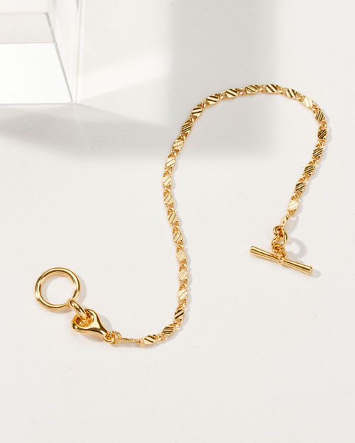 Gold-plated Adorned Toggle Bracelet, with a unique bar and eye closure, on a white surface.