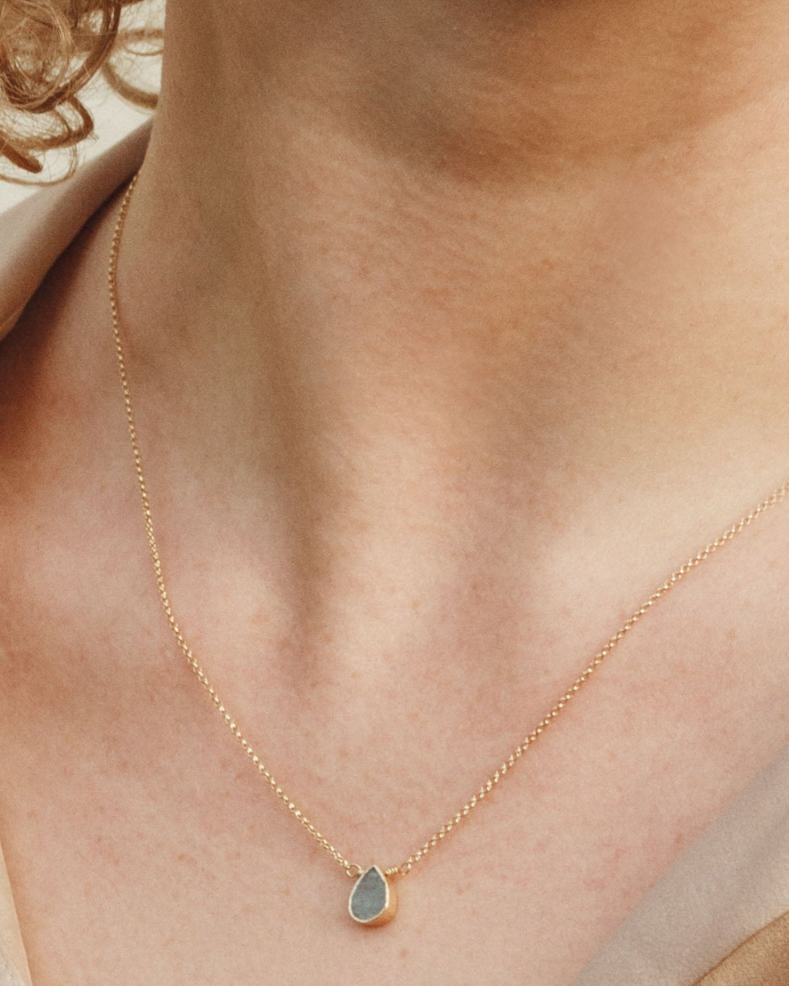 Close-up of a woman's neckline wearing the gold-plated aquamarine Gemstone Birthstone Necklace.