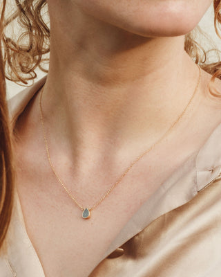 Closeup of a woman's neckline wearing the 14kt gold plated brass aquamarine Delicate Gemstone Birthstone Necklace by Luna Norte.