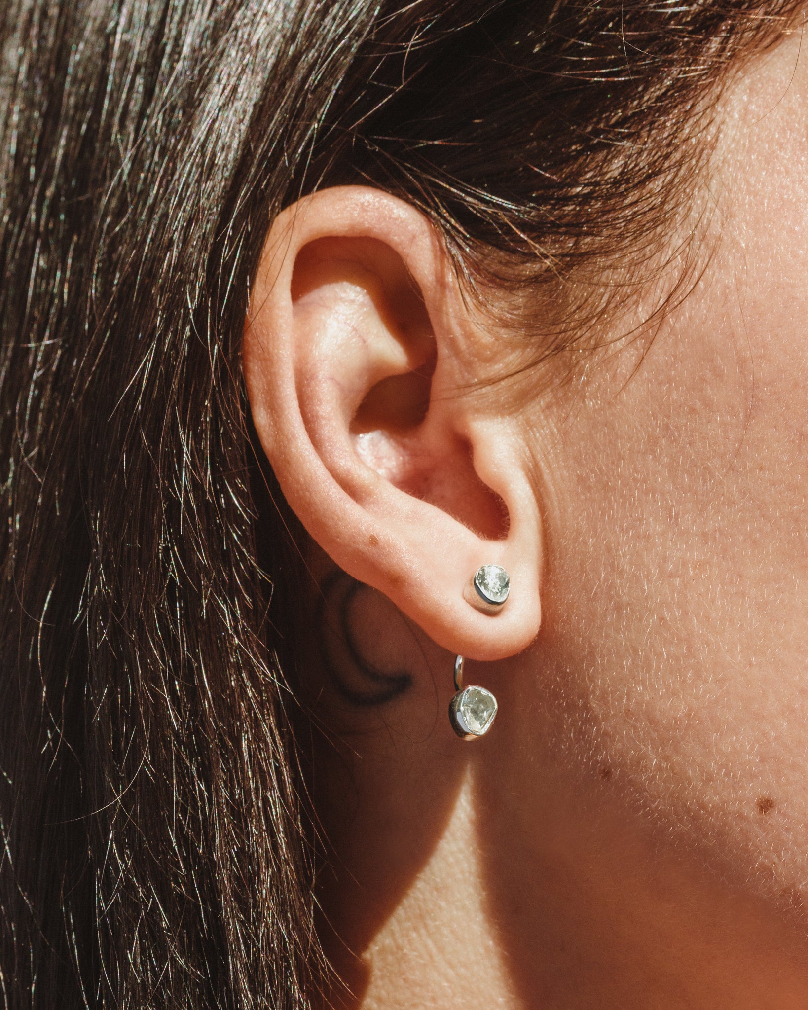 Ear with Double Trouble earrings, aquamarine gemstones in a bezel setting shown.