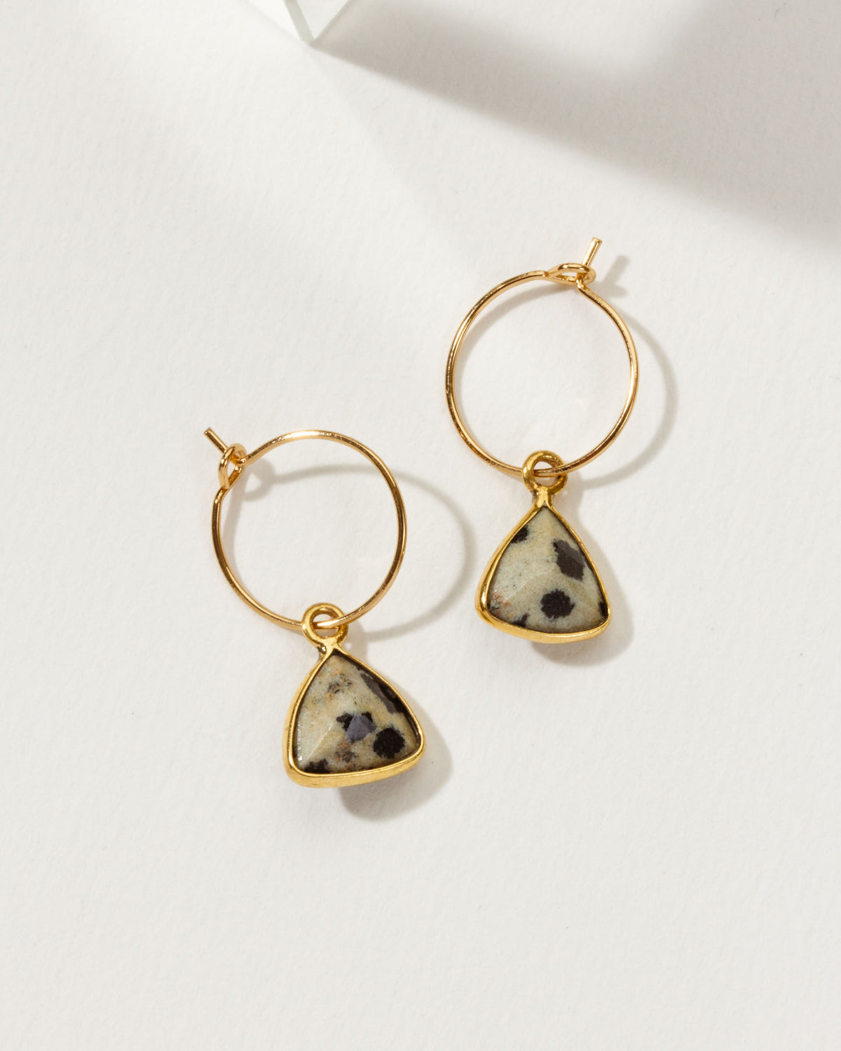 Bermuda Triangle Mini Hoops in Dalmatian Jasper, with gold hoops and triangle-cut gemstone pendants.