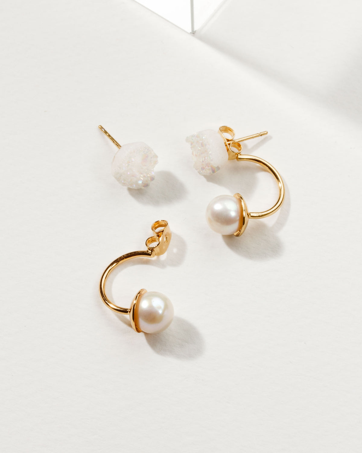 Earrings made of a druzy post with a pearl drop on gold colored metal.
