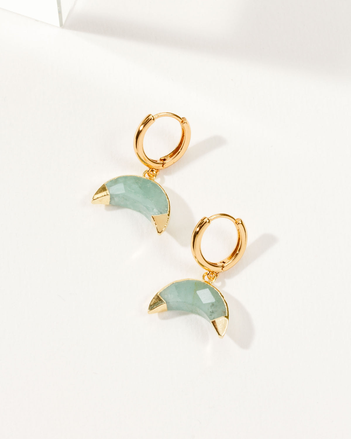 Crescent horn huggie hoop earrings with Aquamarine gemstones and gold-tone hardware.