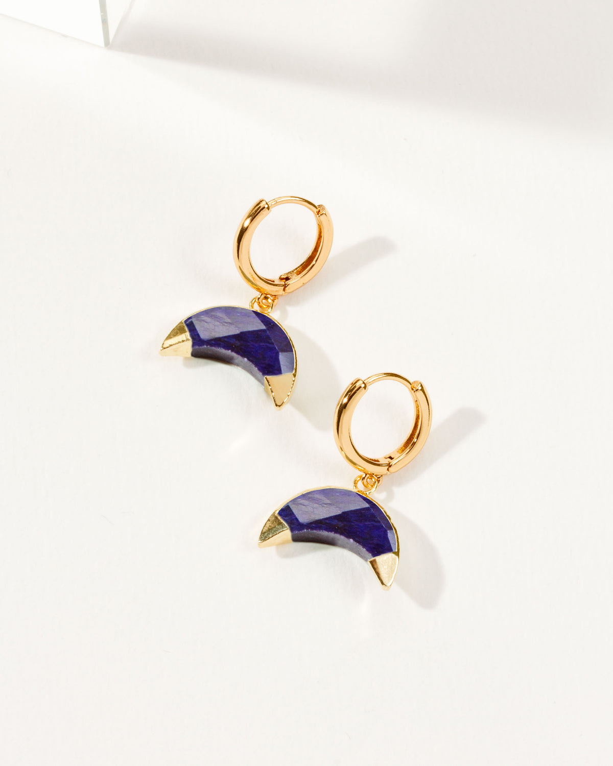 Crescent Horn Huggie Hoop Earrings with Sapphire gemstones and gold hardware.