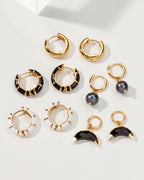 Arrangement of gold hoop earrings with onyx, moonstone, black, and white enamel details.