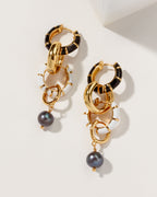 Pair of Jump Through Hoops earrings with black, white, and gold hoops and a dangling dark pearl.