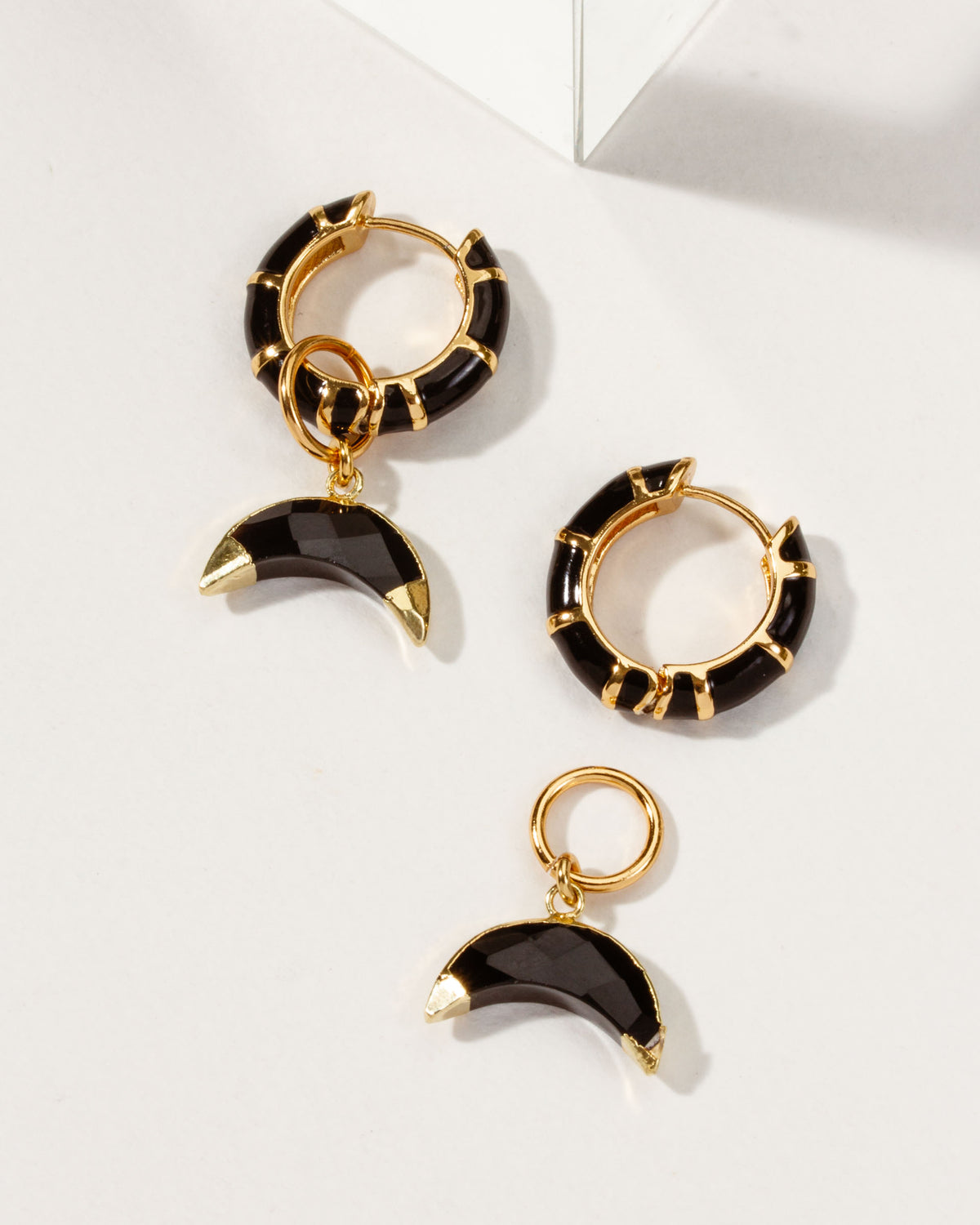 Gold hoop earrings with black enamel and faceted onyx gemstone charms.