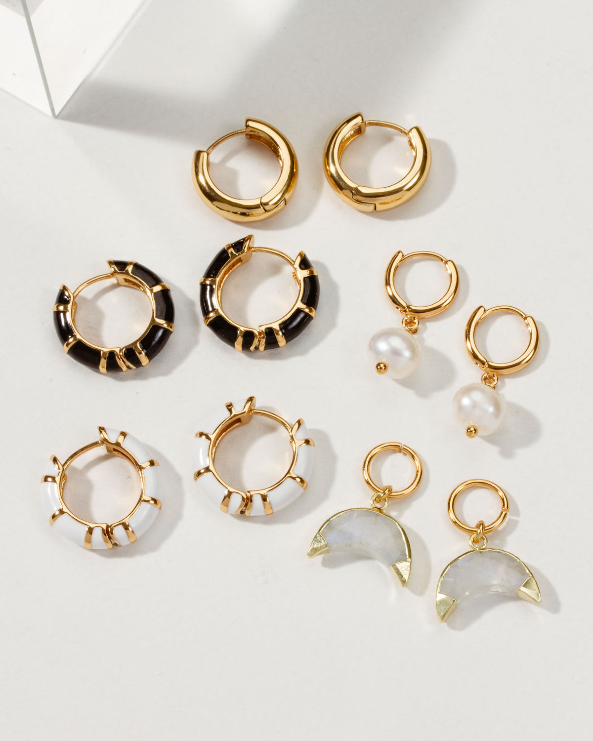 Assorted gold Jump Through Hoops Interchangeable Earrings with onyx, pearl, and moonstone charms.