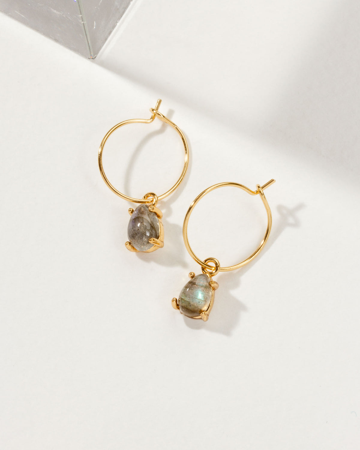 Two gold Airy Hoop Earrings with Labradorite gemstones are displayed on a white surface.