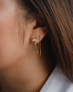 Close-up of an ear wearing a gold Ethereal Post Threader Earring with a grey stone.