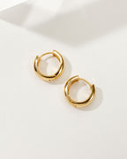 Pair of gold Huggie Hoop Earrings on a white background.