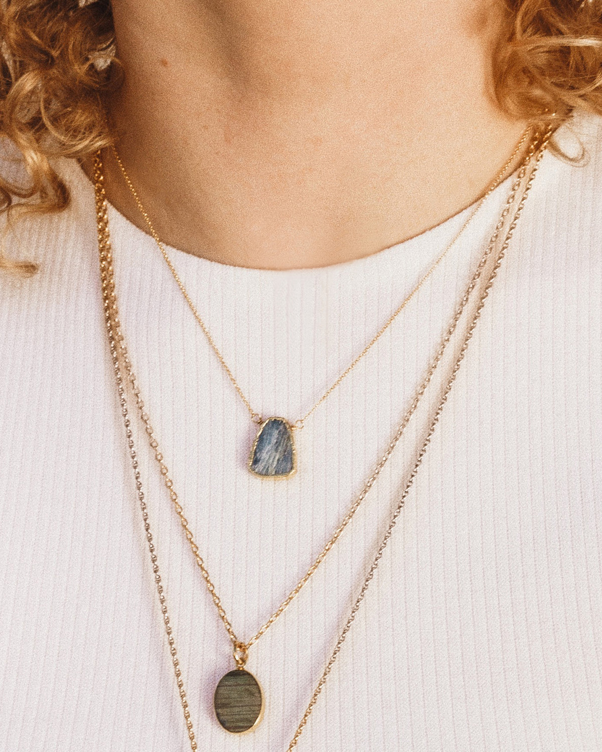 Woman wearing Kyanite Earth, Wind, and Fire necklace layered with two longer necklaces