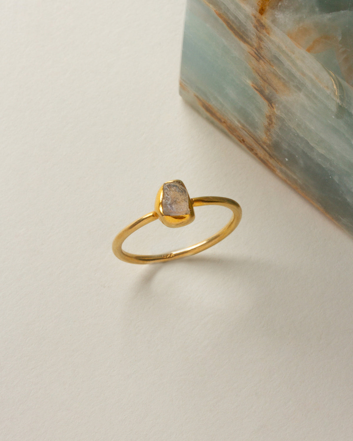 A gold Firefly ring featuring a raw labradorite stone.