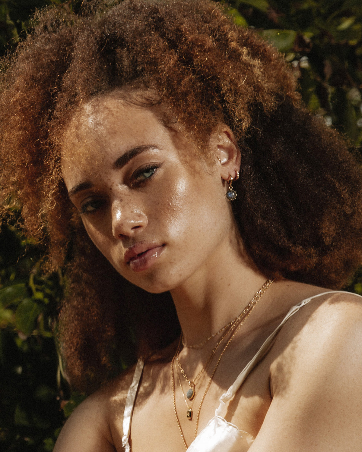 Person wearing gold-plated Flower Power earrings with labradorite flower charms