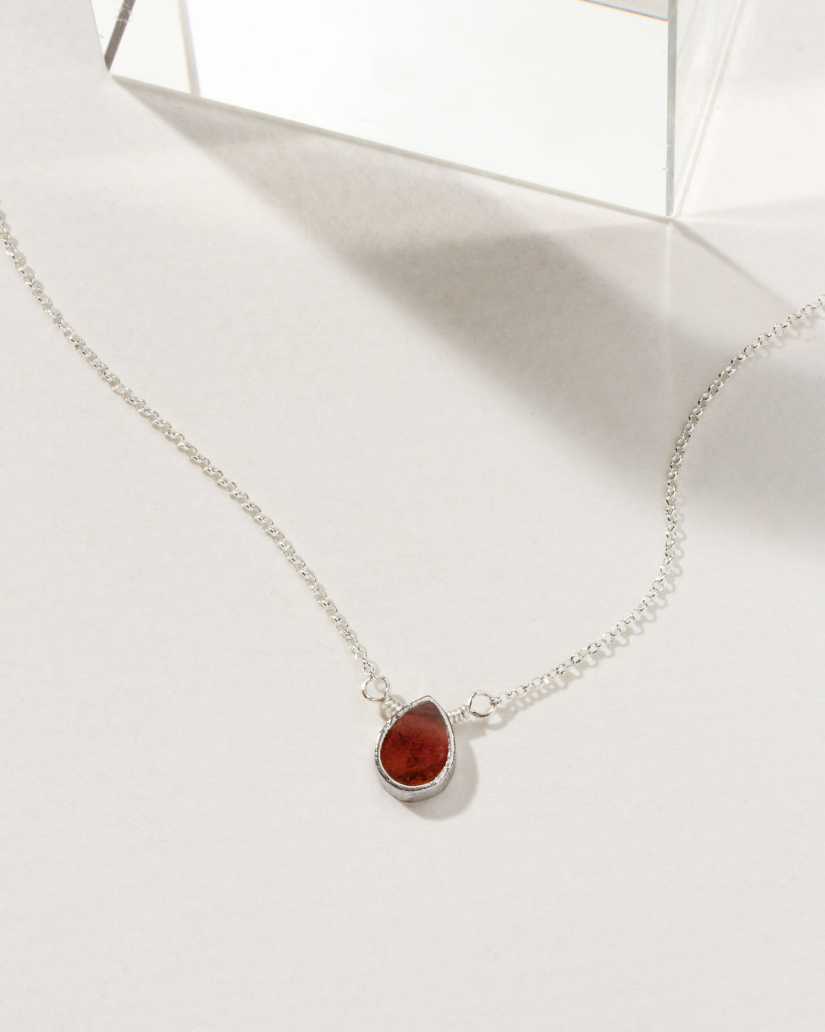 Silver plated brass necklace with a red garnet gemstone pendant.