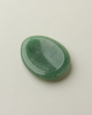 A smooth green aventurine stone with a slight indent, placed on a white surface.