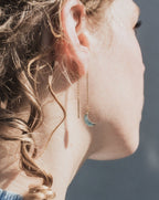 Woman wearing gold Eclipse Threader earring with aquamarine crescent moon charm