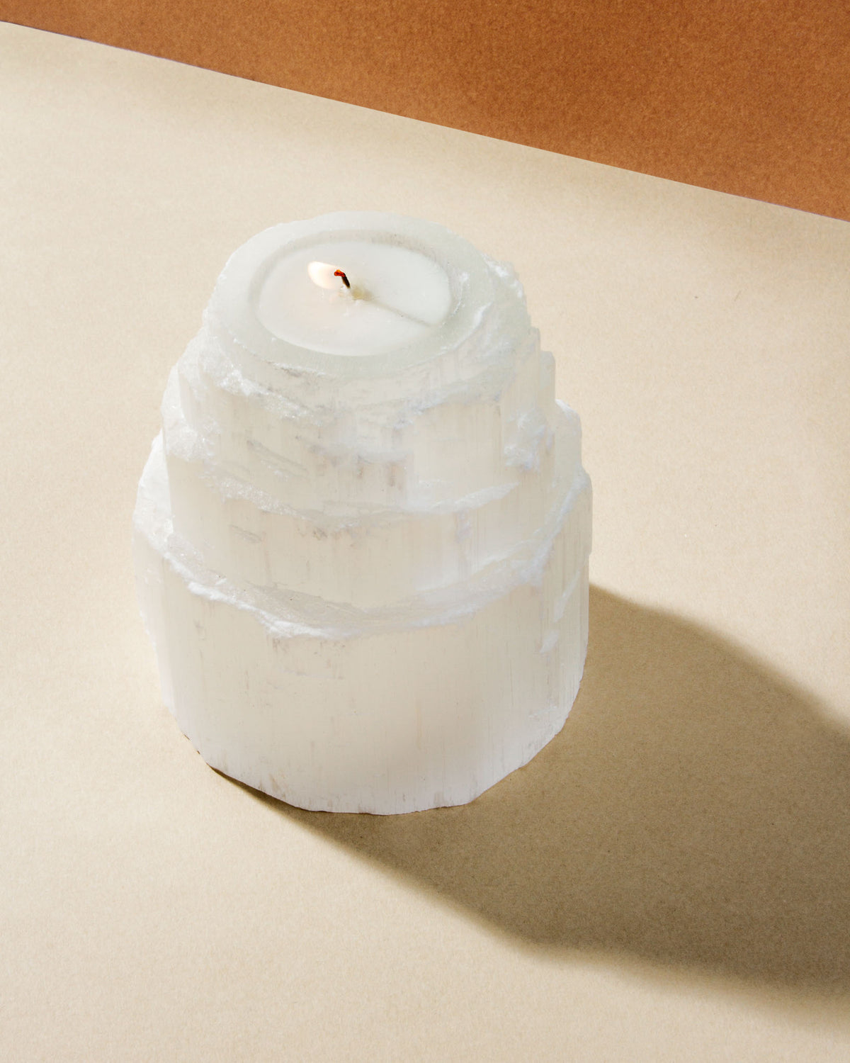 Lit Selenite candle holder is tiered.