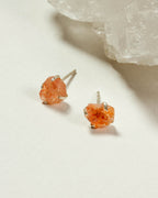 Sterling silver post earrings with raw sunstone gems are displayed on a white surface.
