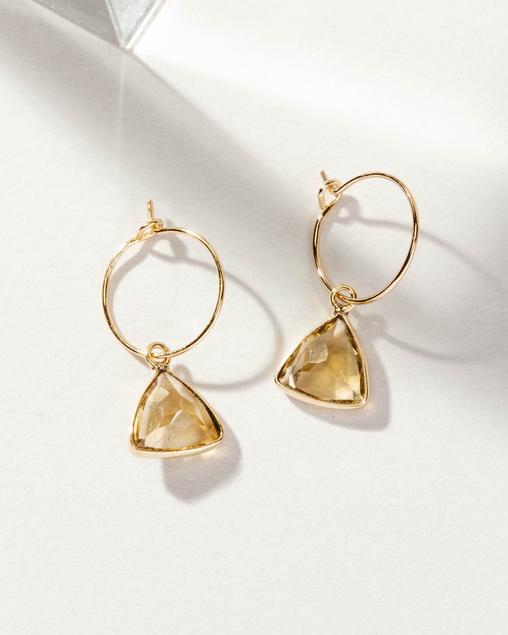 Two Bermuda Triangle Mini Hoops with citrine gemstones and gold hoops are displayed.