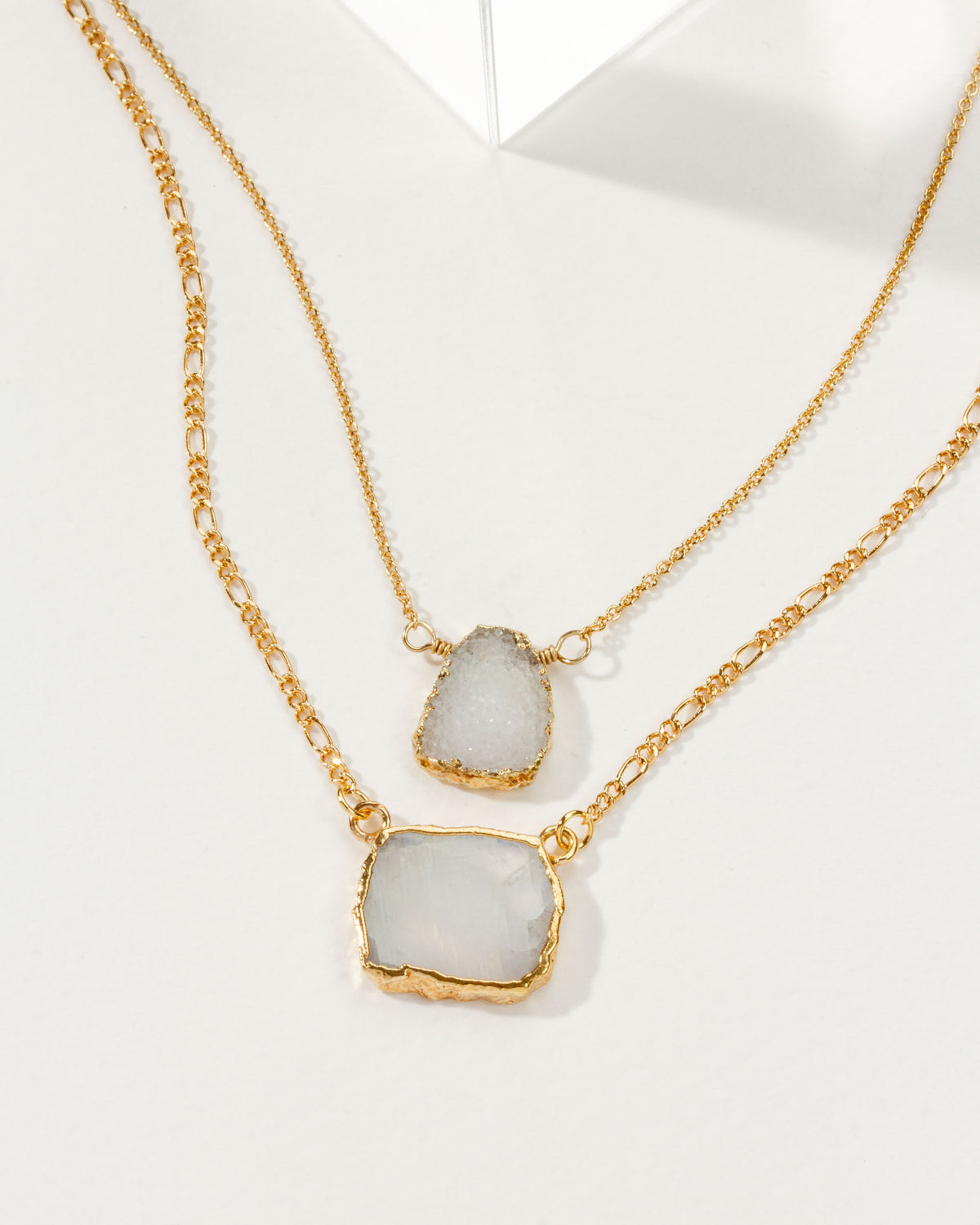 Layered necklace with gold chains and rainbow moonstone & druzy pendants.