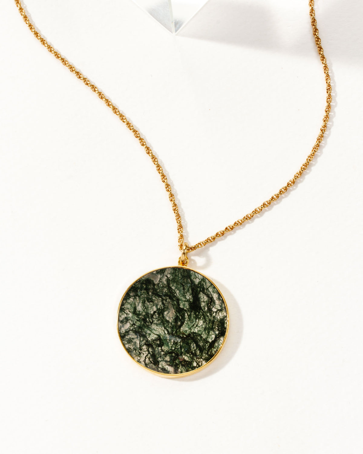 Gold chain necklace with a circular Moss Agate medallion pendant.