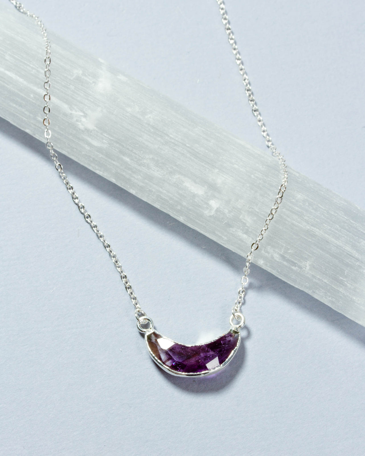 Eclipse Necklace with a silver chain and amethyst gemstone crescent moon pendant.