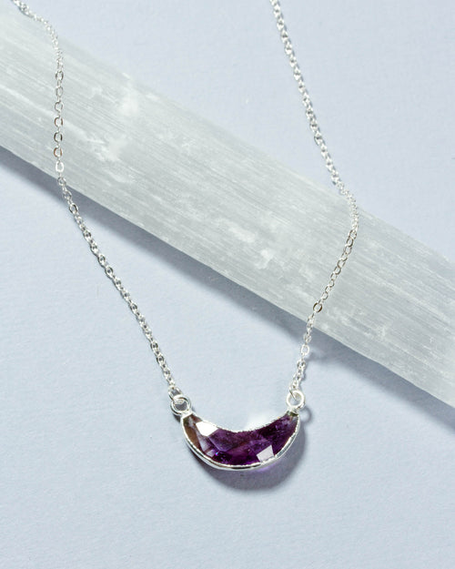 Eclipse Necklace with a silver chain and amethyst gemstone crescent moon pendant.